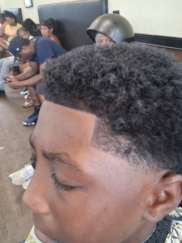 Full afro tapered at the temple with a crisp edge-up along the hairline.