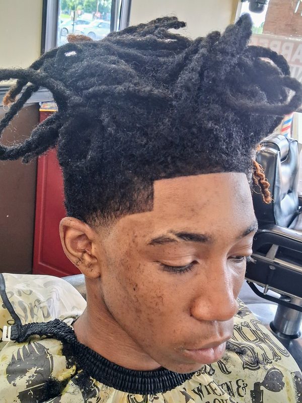 Client with locs pinned up top, faded sides and a squared-off line-up.